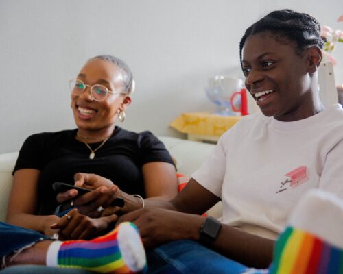 Image of two happy people with rainbow socks on. Learn how to provide the best care for the queer community from compassionate and skilled LGBTQ+ Clinical Consultation mental health professionals.